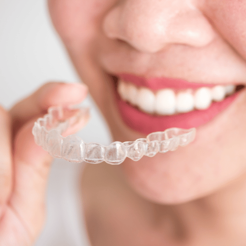 A woman smiling holing Invisalign